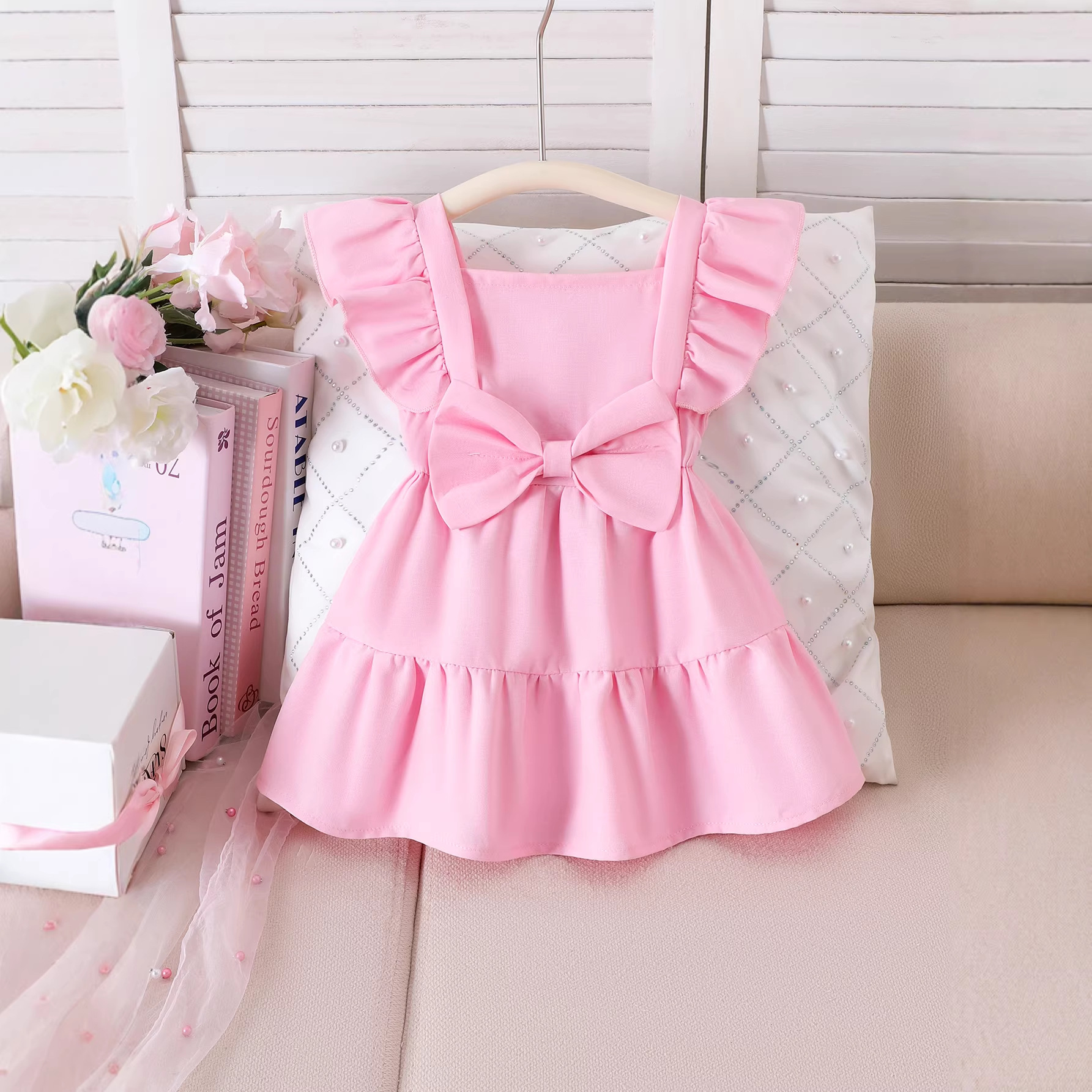 Sweet pink dress for girls in summer with flying sleeves and a large bow on the chest, ruffled hem, and princess skirt design
